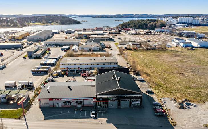 Flygbild över Stenungsund Företagscenter med parkering framför byggnaderna och vatten i bakgrunden